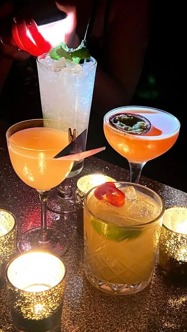 The video showcases Escapologist Bar, a London bar with a quirky, 1899-themed interior. It features various cocktails presented in unique glassware, with some garnishes. The lighting is dim and atmospheric, using red and warm tones. The video focuses on the ambiance of the bar and cocktails, emphasizing the experience rather than detailed food/drink descriptions.