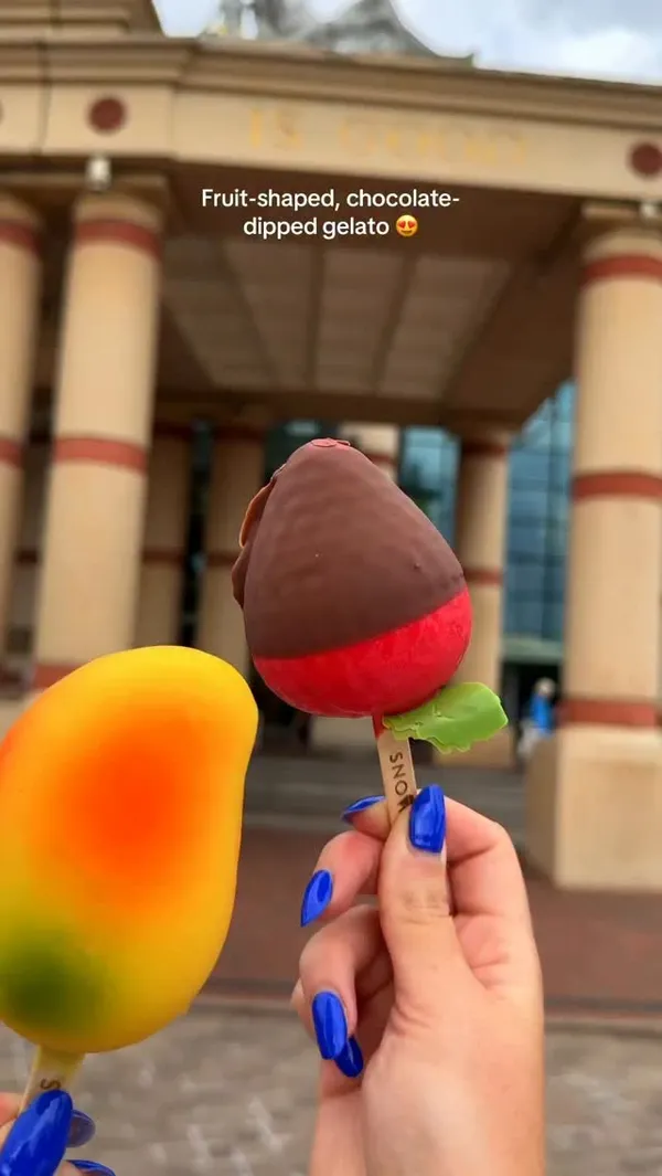 The video showcases fruit-shaped gelato from a pop-up called Snowflake Gelato, located in Westfield London. It features close-ups of mango and strawberry-shaped gelato popsicles, a view of the gelato counter with various options including lemon-shaped gelato, and a child eating a strawberry gelato.