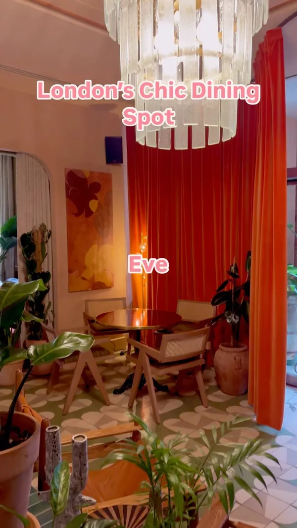 The video showcases the interior and food offerings of Eve, a restaurant in Kensington, in collaboration with Proper Slice. The setting includes indoor dining areas with plants and natural light. Food items shown are a pepperoni pizza, a pesto pizza, and a Caesar salad. The pizzas are presented on metal trays with red and white checkered paper. Drinks include orange cocktails with straws. The main focus is on highlighting the restaurant's ambiance and the food available.