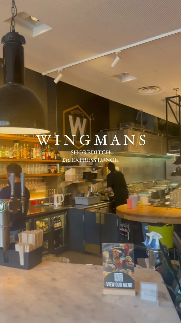 This video showcases Wingman's restaurant in Shoreditch, London.  It highlights their £12 express lunch deal, featuring buffalo wings (with a close-up shot emphasizing the meatiness and sauce), french fries, and a side of sauce.  The video shows the restaurant's interior and exterior, and the influencer enjoys their meal.  No specific dietary information is provided.