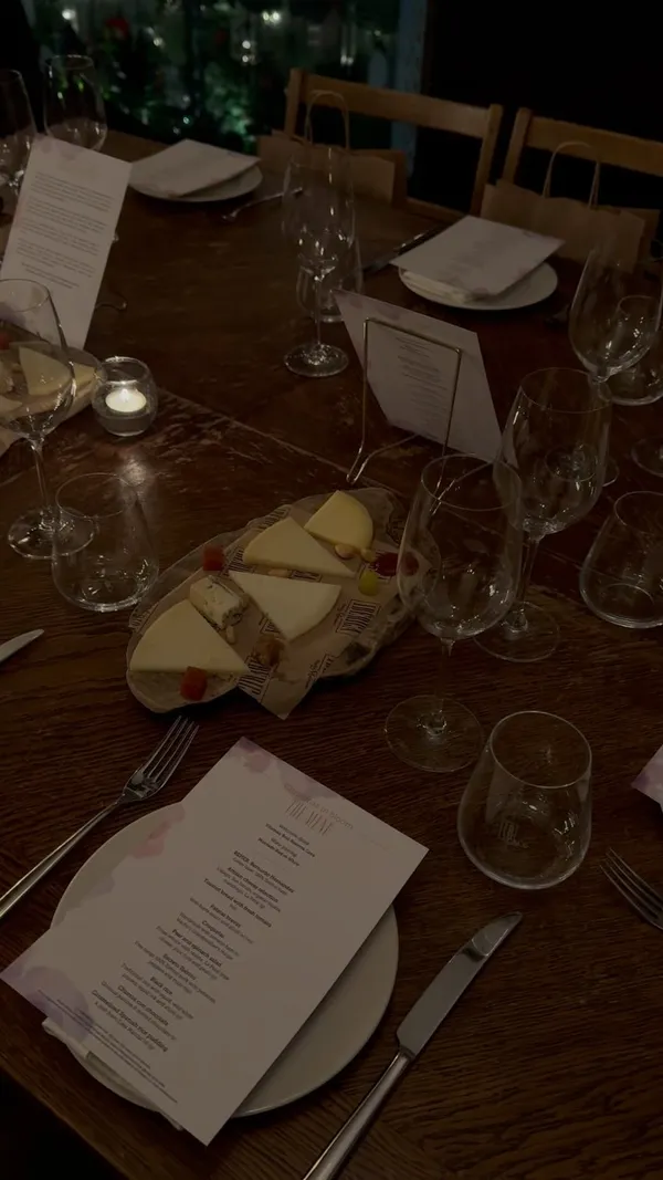 The video showcases a Christmas-themed dinner event at Iberica Restaurants in London. It features various dishes, including artisan cheese, patatas bravas, croquettes, a pear and spinach salad, and a main course of pork. The setting is a dimly lit, elegant restaurant with a long wooden table set for a group dinner. The presentation emphasizes the ambiance and the food's visual appeal, though the dark lighting obscures some details.  No dietary information is explicitly mentioned.