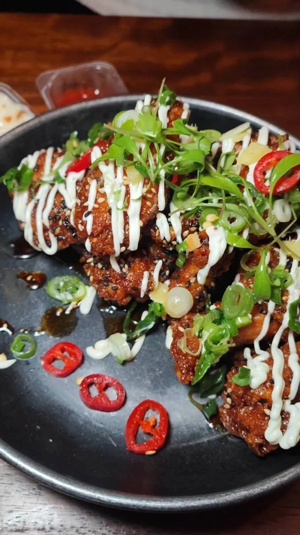 The video showcases a bottomless brunch at Wingmans Chicken.  It features various close-up shots of their chicken wings in different flavors, including buffalo, sweet & smokey BBQ, bangcoq, szechuan, Jamaican, and shanghai oriental. The wings are served with sauces, spring onions, and sesame seeds. The video also includes a shot of the restaurant's exterior and mentions the £45 price point.