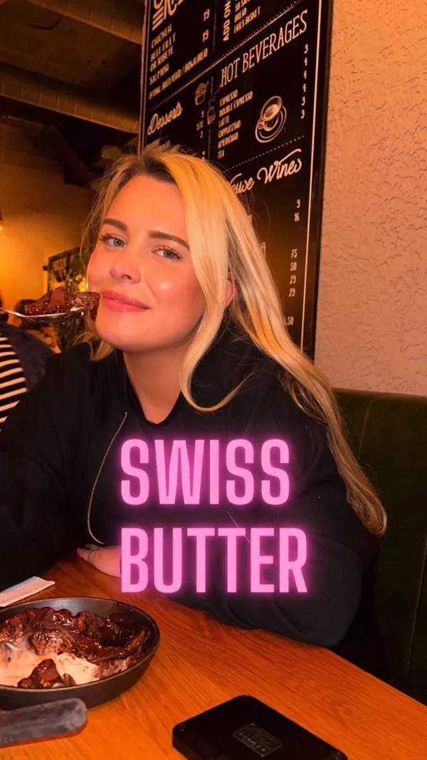 The video showcases a restaurant meal in London, specifically highlighting the "Swiss Butter" dish. The dish includes sliced steak in a yellow sauce, served with french fries and a side salad. The setting is a restaurant with a wooden table. The presentation focuses on the close-up of the steak dish, emphasizing the sauce and the texture of the steak. No dietary information is explicitly provided. The main focus is on presenting the food.