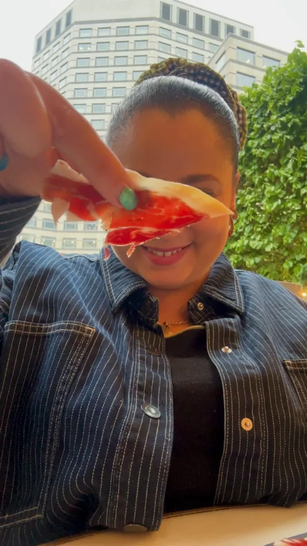 The video showcases La Terraza, a new outdoor tapas restaurant at Canary Wharf. It features various tapas dishes like small sandwiches with tomato and cheese, a selection of cheeses, a salmon sandwich, and other meat-based tapas. The setting is a beautifully decorated outdoor space with water features and heating lamps.  The food is presented attractively, using natural lighting, and the overall atmosphere is vibrant and inviting.