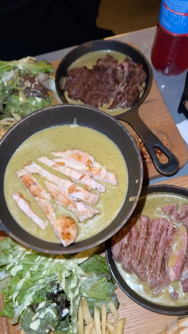 The video showcases Swiss Butter restaurant in Holborn, London. It features various dishes, including rib eye steak, beef, salmon, and chicken, all served with Swiss butter sauce, fries, and bread.  The restaurant is presented as Halal.  The video also shows chocolate lava cakes and a refreshing drink. The main focus is on the food presentation and the restaurant's ambiance.