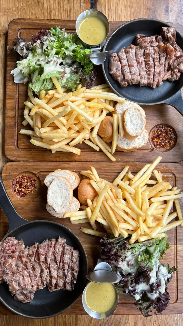 The video features an influencer visiting Swiss Butter restaurant in London. It shows the exterior and interior of the restaurant, followed by close-ups of their signature steak frites with secret sauce, a wagyu burger, molten chocolate dessert, and pain perdu. The influencer tries the food, dips steak and bread in the sauce, bites into the burger, and tastes the desserts, providing ratings and commentary on the taste and value.