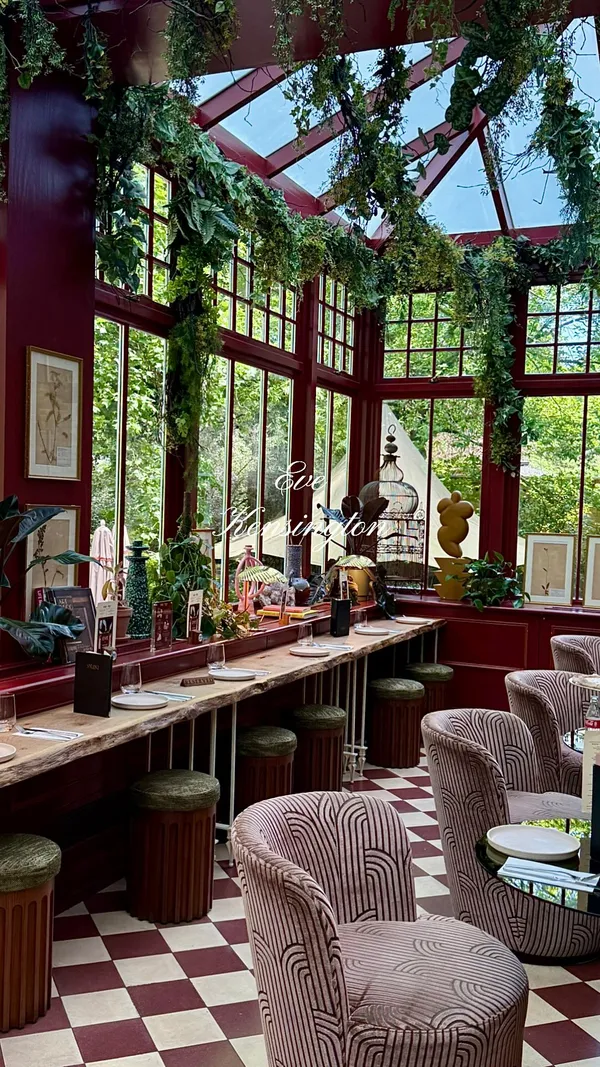 The video showcases Eve Kensington restaurant located within Ember Locke. It features the restaurant's stylish interior with large windows, plants, and unique decor. The video highlights various dishes including pepperoni pizza, mac & cheese, buffalo wings, parmesan chips/fries, burrata with pesto, chocolate brownie, and pistachio gelato, along with cocktails and iced coffees. The food is presented on tables with place settings.