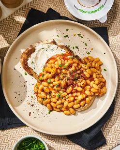 Vegan beans on toast with almond spread, topped with chives and chili flakes for a cozy weekend brunch.