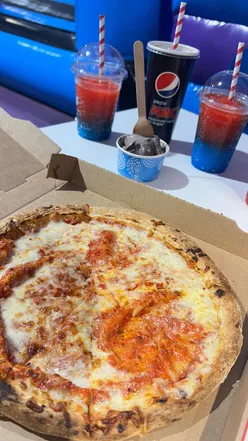 Families enjoying inflatables and delicious pizza at InflataNation, a perfect rainy day activity for kids.