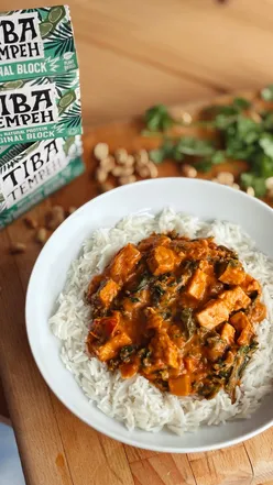 “Delicious peanut red curry with tiba tempeh, served with basmati rice, peanuts, and lime for a cozy meal.”