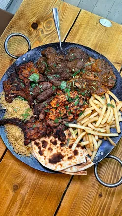 Delicious sharing platter with chicken tikka, lamb chops, and naan at a vibrant restaurant in Hertfordshire.