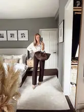 Fashionable woman in heels, coffee in hand, ready for a meeting but heading to Starbucks casually.