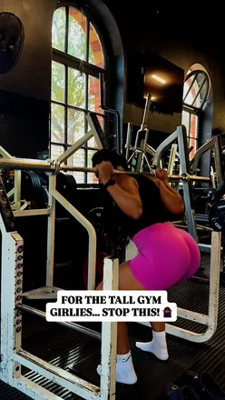 Fit female gym-goer showcasing a barbell squat, emphasizing tall girls' unique muscle distribution and fitness goals.