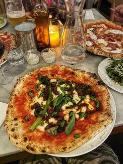 Delicious vegan 'nduja pizza, tiramisu espresso martini, and vibrant salads at Rudy's Pizza in London.