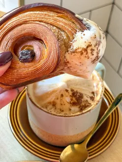 Enjoying a buttery pain au chocolat and apple cinnamon pastry with cappuccino at Jeju Bakes in Glasgow.