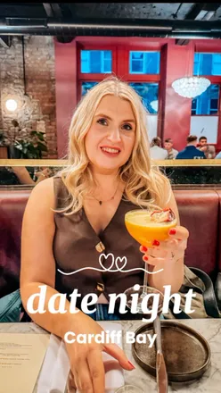 Couple enjoying a warm focaccia and drinks at Aura, Cardiff Bay, perfect for a romantic night out. 🍽️💖