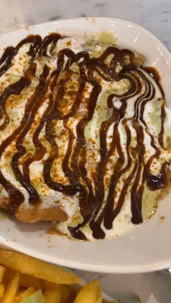 Diners enjoying Samosa Chaat, Meat Lasagne, and Chicken Tikka on Naan at Cafe Janan, blending flavors in Bradford.