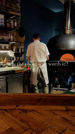 Customers enjoying delicious pizzas and small plates at Flint Pizza in Newcastle, showcasing vibrant food and lively atmosphere.