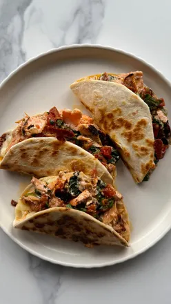 Delicious Marry Me Salmon Tacos featuring seasoned salmon, sun-dried tomatoes, and spinach in a tortilla wrap.