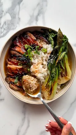 Delicious miso ginger chicken brothy rice with caramelized chicken, sticky rice, and charred pak choi in a bowl.