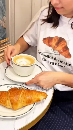 Enjoying a croissant and coffee at PAUL Marylebone, featuring Uniqlo's limited edition collab tee.