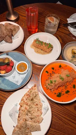 Couple enjoying Mediterranean small plates and cocktails at Hovarda, a chic date night spot in Canary Wharf.