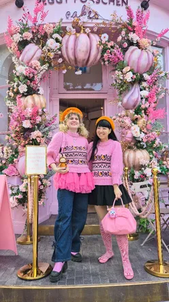 Two friends enjoying tea and cute Halloween-themed cakes at Peggy Porschen in London, dressed in matching outfits.