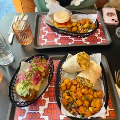 Brunch spread featuring a breakfast burrito, avocado crema hash browns, and a breakfast muffin at The Saucy Cow, Dublin.