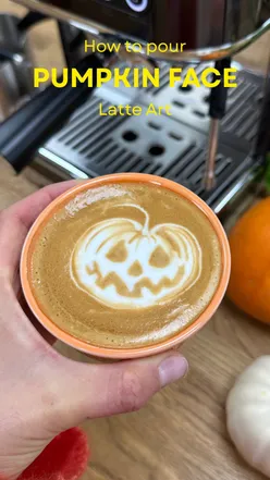 Barista pouring a pumpkin face latte using the Philips Barista Brew espresso machine for fall coffee lovers.