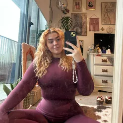 Person taking a selfie with cats surrounded by colorful tattoos and a playful expression.