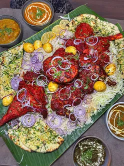 Group enjoying a festive MEGA XMAS FEAST at De Baga in Chapel Allerton, featuring Indian cuisine and holiday vibes.