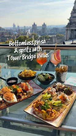 Guests enjoying bottomless pinsa and spritz with a stunning Tower Bridge view at Savage Garden, London.