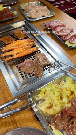 Dining at a Chinese BBQ in Manchester, grilling meats at the table for a smoky flavor experience.