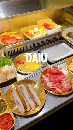 Guests enjoying all-you-can-eat hotpot and K-BBQ at DAIU in London, featuring vibrant dishes and a clean atmosphere.