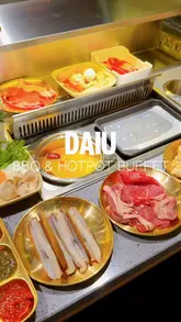Guests enjoying all-you-can-eat hotpot and K-BBQ at DAIU in London, featuring vibrant dishes and a clean atmosphere.