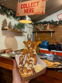 Delicious food stalls at Manchester Christmas Markets 2025, featuring churros, hot chocolate, pancakes, and K dogs.