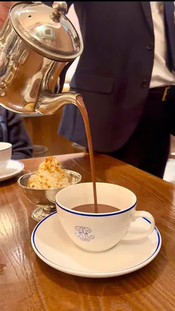 Enjoying festive afternoon tea at Richoux, featuring sandwiches, scones, and decadent hot chocolate in London.