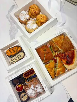 Gorgeous takeaway afternoon tea box from @mogi.cafe with savory treats, scones, and sweet delights in a stylish presentation.