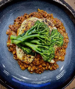 Delicious flattened chicken breast with lentils and tenderstem broccoli, showcasing a vibrant, hearty meal at home.
