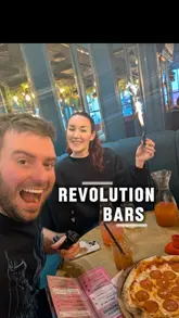 Group enjoying pepperoni pizza and colorful cocktail pitchers at Revolution Brighton, savoring a fun night out.