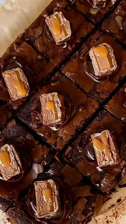 Decadent Mars Bar brownies topped with ganache and caramel, perfect for a cozy winter treat at home.