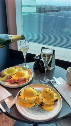 Enjoying bottomless food and champagne at No1 Lounges in Gatwick before my flight, featuring eggs Benedict and cocktails