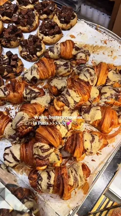 Indulging in a crookie, the iconic cookie-croissant hybrid, outside Maison Louvard in vibrant Paris.