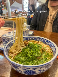 Couple enjoying hand-pulled noodles and biang biang noodles at Kung Fu Noodle in Manchester's Chinatown.