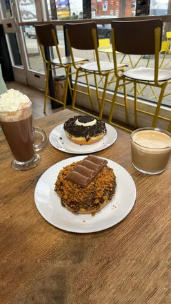 Enjoying giant doughnuts and hot drinks at a cozy West Bridgford cafe, perfect for a date or catch-up!