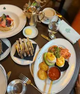 A high-angle flat lay shot of a breakfast spread at The Ivy, featuring a vegetarian breakfast, buttermilk pancakes, and hot drinks.