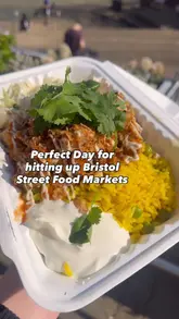 A vibrant dish of KC Peri Peri chicken served with rice, slaw, spicy sauce, and black garlic mayo at a Bristol food market.
