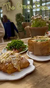 A montage video showcasing 'The Green Room' cafe, highlighting its bright interior, outdoor seating, live music, and a selection of food and drinks including focaccias, open sandwiches, and pastries.