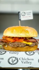 A creator visits the newly opened Chicken Valley in Lansdowne, Bournemouth. The video features a tour of the kitchen, showing the preparation of fried chicken, a smash burger, and Korean wings, followed by a review of the final dishes.
