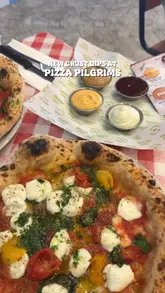 A creator visits Pizza Pilgrims to review their new collaboration crust dips, featuring sauces from Dishoom, Sweet Dee's Jerk, Honest Burgers, and Pho.